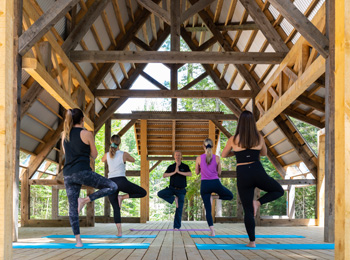 cours de yoga sous un toit de bois en plein air au Baluchon Éco-villégiature.