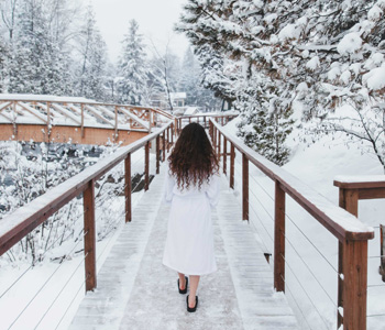 Femme se dirigeant vers le pont en hiver au Strøm spa nordique Saint-Sauveur