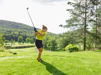 Femme sur un terrain de golf s'apprêtant à frapper la balle. 