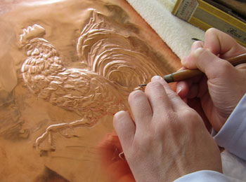 Artiste en train d’embosser une feuille de cuivre