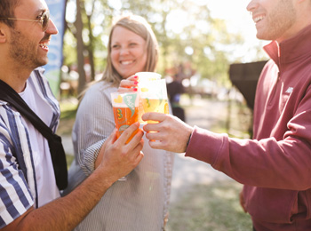 Trois personnes en train de trinquer avec un verre de bière en main.