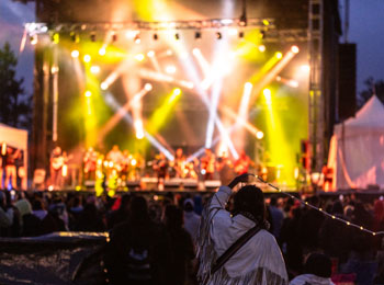 Scène illuminée avec spectacle en fin de soirée pendant le festival Innu Nikamu.