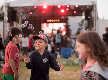3 enfants qui s'amusent devant la scène au festival.
