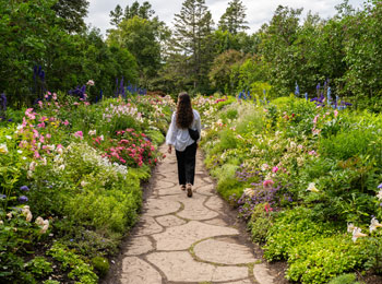 Femme qui marche qui traverse un jardin fleuri.