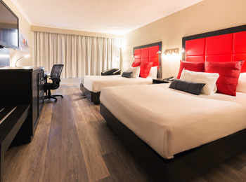 Intérieur d’une chambre d’hôtel aux accents rouges avec deux grands lits